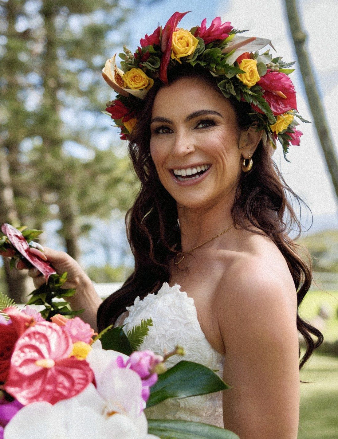Samantha on her wedding day in Hawai&lsquo;i, laughing, in a crown of tropical flowers, holding a lei and a bouquet